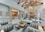 Thumbnail 46 of 68 - A large, modern living room with a stone fireplace and a high ceiling with exposed beams at Limestone Ranch Apartments, Texas, 75067