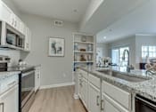 Thumbnail 3 of 68 - A kitchen with white cabinets and granite countertops at Limestone Ranch Apartments, Texas