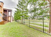 Thumbnail 55 of 68 - A black metal fence runs along a grassy area at Limestone Ranch Apartments, Lewisville