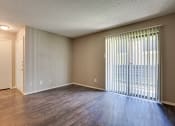 Thumbnail 3 of 32 - an empty living room with a large window and wood flooring at The Manhattan Apartments, Dallas, TX, 75252