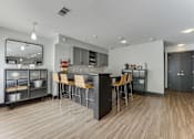 Thumbnail 35 of 51 - A modern kitchen with a wooden floor and a large island with chairs. at The Manhattan Apartments, Texas