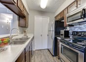 Thumbnail 13 of 51 - A kitchen with a white fridge and black stove. at The Manhattan Apartments, Dallas, TX