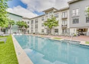 Thumbnail 37 of 52 - Outdoor swimming pool surrounded by landscaped courtyard at The Montrose Apartments, Texas