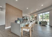 Thumbnail 18 of 52 - Communal kitchen island with seating and vertical slat partition at The Montrose Apartments, Dallas, Texas