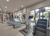 Thumbnail 46 of 52 - Fitness center with cardio equipment and large windows at The Montrose Apartments, Dallas, TX