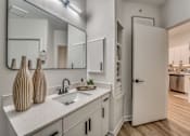 Thumbnail 10 of 52 - Bathroom vanity with white cabinetry and recessed shelving at The Montrose Apartments, Dallas