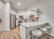Thumbnail 2 of 52 - Modern kitchen with white countertops and bar seating at The Montrose Apartments, Texas, 75204