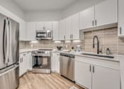 Thumbnail 3 of 52 - Modern kitchen with white cabinetry and stainless appliances at The Montrose Apartments, Dallas, TX 75204