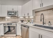 Thumbnail 4 of 52 - Modern kitchen with stainless steel appliances and tile backsplash at The Montrose Apartments, Dallas, TX