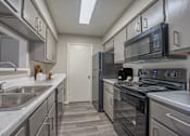 Thumbnail 4 of 41 - A kitchen with a black stove top oven and a black microwave above it.