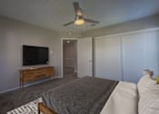 Thumbnail 10 of 41 - A bedroom with a bed, a television, and a ceiling fan.