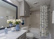 Thumbnail 8 of 41 - A bathroom with a white toilet, a sink, a mirror, and a shower.