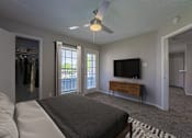 Thumbnail 11 of 41 - A bedroom with a bed, a dresser, a TV and a ceiling fan.