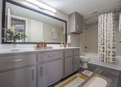 Thumbnail 12 of 41 - A bathroom with a sink, mirror, toilet, and shower.