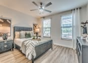 Thumbnail 8 of 53 - Bedroom with ceiling fan and wood style flooring at The Barton Apartments, Texas