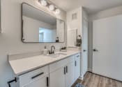 Thumbnail 11 of 53 - Bathroom vanity with modern fixtures and large mirror at The Barton Apartments, Dallas, TX 75206