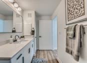 Thumbnail 10 of 53 - Modern bathroom with white vanity and wood flooring at The Barton Apartments, Dallas, TX