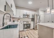 Thumbnail 4 of 53 - Modern white kitchen with stainless steel appliances and island at The Barton Apartments, Texas