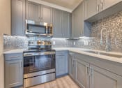 Thumbnail 4 of 29 - A modern kitchen with a stove top oven and microwave.