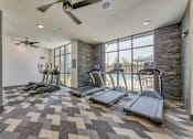 Thumbnail 16 of 29 - A gym with treadmills and a fan.