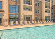 Thumbnail 13 of 29 - A large swimming pool in front of a building with lounge chairs around it.