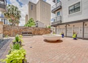 Thumbnail 34 of 37 - Courtyard plaza with decorative fountain and brick pavers at Vue Live Oak Apartments, Dallas