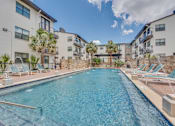 Thumbnail 26 of 37 - Resort style pool with stone wall and lounge chairs at Vue Live Oak Apartments, Dallas, TX