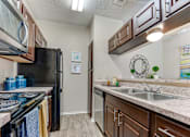Thumbnail 7 of 39 - A kitchen with a black refrigerator and brown cabinets. at Wilson Crossing, Cedar Hill