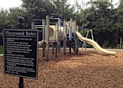 Thumbnail 6 of 7 - A playground with a sign that lists the rules.
