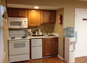 Thumbnail 1 of 13 - A kitchen with white appliances and wooden cabinets.