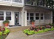 Thumbnail 7 of 13 - A house with a front porch and a flower bed in front.