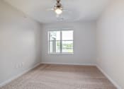 Thumbnail 7 of 19 - A room with a ceiling fan and carpeted floor.