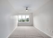 Thumbnail 9 of 19 - A spacious room with a ceiling fan and a large window.