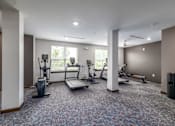 Thumbnail 18 of 19 - A spacious gym with treadmills, elliptical machines, and other exercise equipment.