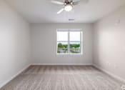 Thumbnail 5 of 19 - A room with a ceiling fan and a window overlooking a balcony.