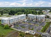 Thumbnail 15 of 19 - A large building complex with a parking lot in front.