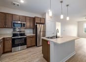 Thumbnail 2 of 19 - A kitchen with wooden cabinets and stainless steel appliances.