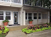 Thumbnail 8 of 13 - A house with a front porch and a flower bed in front.