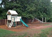 Thumbnail 10 of 13 - A playground with a green slide and a wooden structure.
