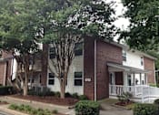 Thumbnail 3 of 9 - A two-story house with a white front porch and a tree in front.