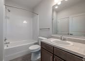 Thumbnail 6 of 19 - A white bathroom with a toilet, sink, and bathtub.