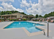 Thumbnail 14 of 22 - A large outdoor swimming pool with a diving board and lounge chairs.
