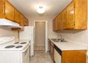 Thumbnail 9 of 22 - A kitchen with white appliances and wooden cabinets.