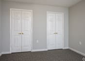 Thumbnail 15 of 25 - Two white doors in a room with carpeted floor.
