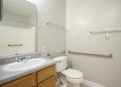 Thumbnail 10 of 25 - A bathroom with a toilet, sink, and towel racks.