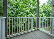 Thumbnail 11 of 25 - A white railing on a wooden deck overlooks a green forest.