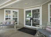 Thumbnail 3 of 25 - A white bench with red and white pillows sits on a porch.