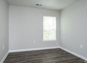Thumbnail 7 of 25 - A room with a window and wooden flooring.