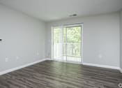 Thumbnail 6 of 25 - A room with wooden flooring and a sliding glass door.