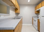 Thumbnail 5 of 25 - A kitchen with a white refrigerator and wooden cabinets.